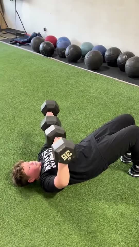 An athlete performs a dumbbell floor press.