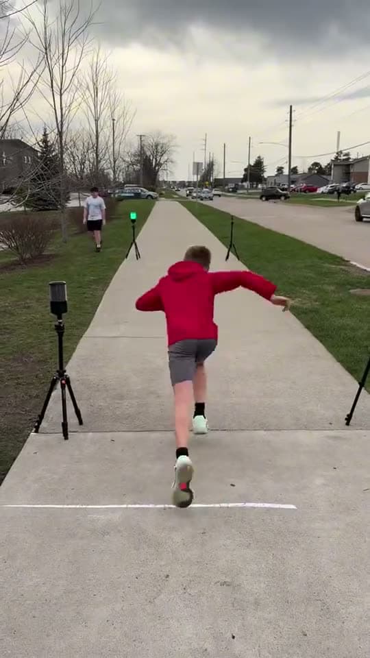 An athlete sprints down an outdoor lane between timing gates.